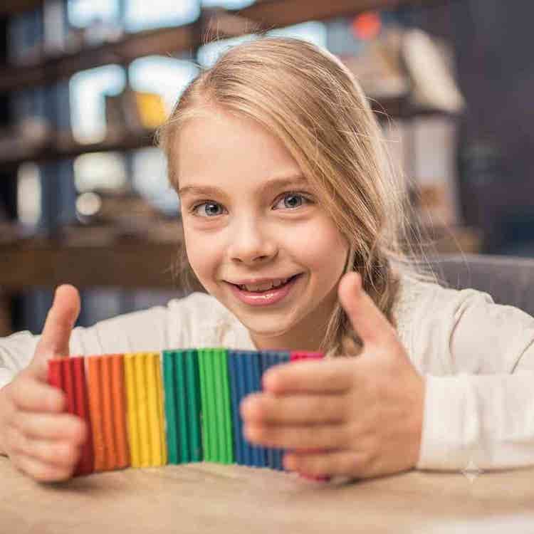 A smiling young girl engages with colorful modeling clay during a structured pediatric sensory integration session at a development center.