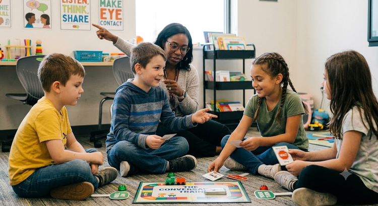 Children interacting and smiling during a collaborative turn-taking board game with therapeutic guidance.