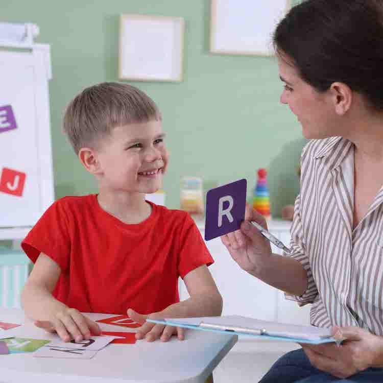 A pediatric speech-language pathologist provides dynamic visual cues to help a child coordinate precise vocal sequences in a clinic.